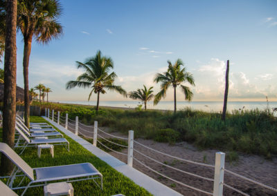 Photo of a grassy area with chaise lounges facing the perfect view of the beach.